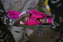 Membros de equipa de resgate transportam numa maca idosa que sobreviveu aos deslizamentos de terra no Nepal