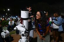 A person observes the full moon through a telescope during