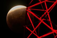 A partial lunar eclipse is seen beyond a television tower