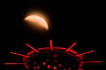 A partial lunar eclipse is seen beyond artwork atop the