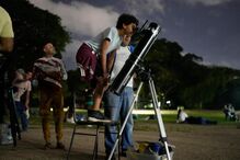 A boy looks at the moon through a telescope during