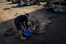 Homem com criança perto de carros destruídos após ataque russo nos arredores de Kiev