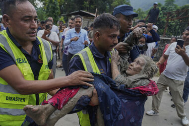 Equipas de resgate carregam mulher, vítima da enxurrada no Nepal, para um local seguro