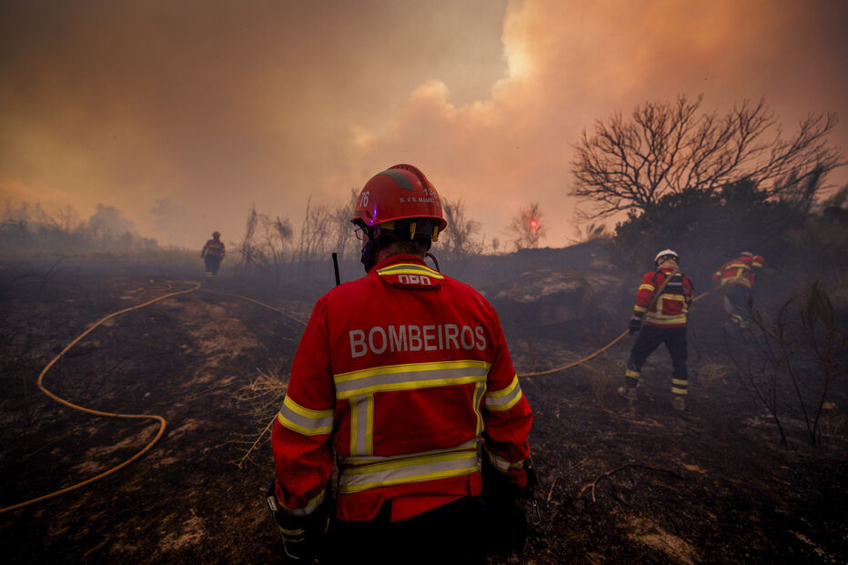 Bombeiros combatem incêndio em área de mato, com fumo a dominar o céu