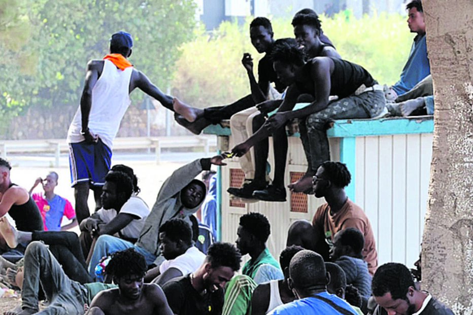 Migrantes em filas perto de uma barreira