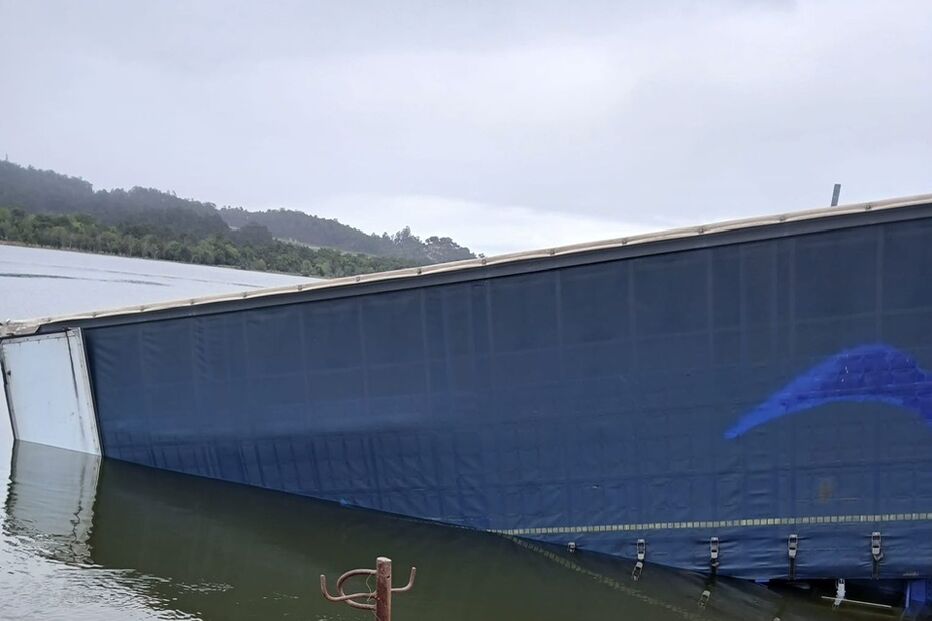 Camião semi-submerso na água perto de um cais de betão