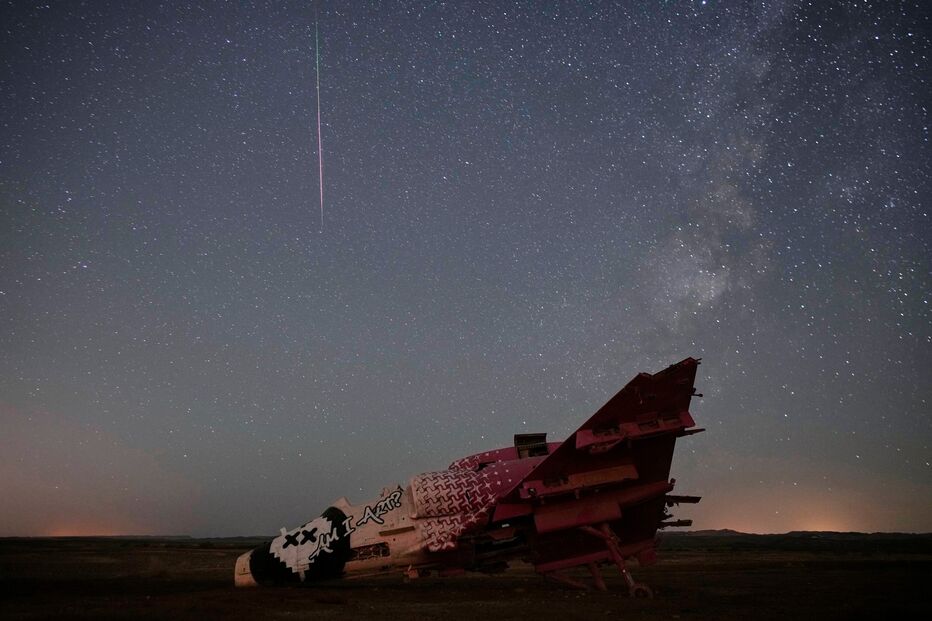 A meteor streaks above a destroyed aircraft used for training purposes in the Negev Desert, Israel, Thursday, Aug. 13, 2026.
