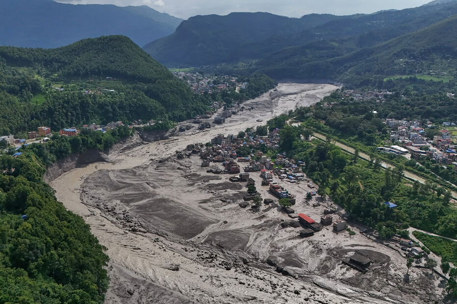 Damaged houses stand precariously near the swollen, debris-choked banks of the Trishuli River after flash floods in Nepal's Nuwakot district