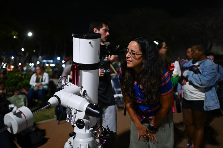 A person observes the full moon through a telescope during