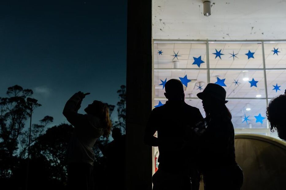 People observe the partial lunar eclipse as seen over a
