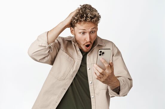 Homem olha espantado para o telemóvel, possivelmente por uma conta de roaming inesperada