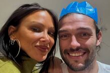 Um casal celebra com uma coroa festiva e um gorro de natal