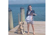 Mulher com bebé e cão num cais junto ao mar