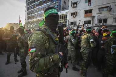 Combatentes das Brigadas Qassam, o braço armado do Hamas, controlam a multidão enquanto veículos da Cruz Vermelha manobram para recolher reféns israelitas que serão libertados ao abrigo de um acordo de cessar-fogo entre Israel e o Hamas, na cidade de Gaza, no domingo, 19 de janeiro de 2025