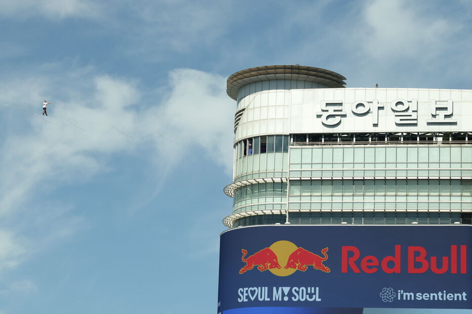 Homem faz slackline junto a edifício com anúncio da Red Bull em Seul