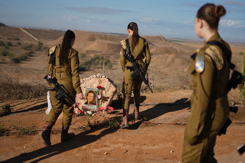 Mulheres em uniforme militar visitam um memorial