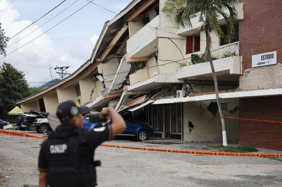 A person looks at buildings damaged by the 7.7-magnitude earthquake